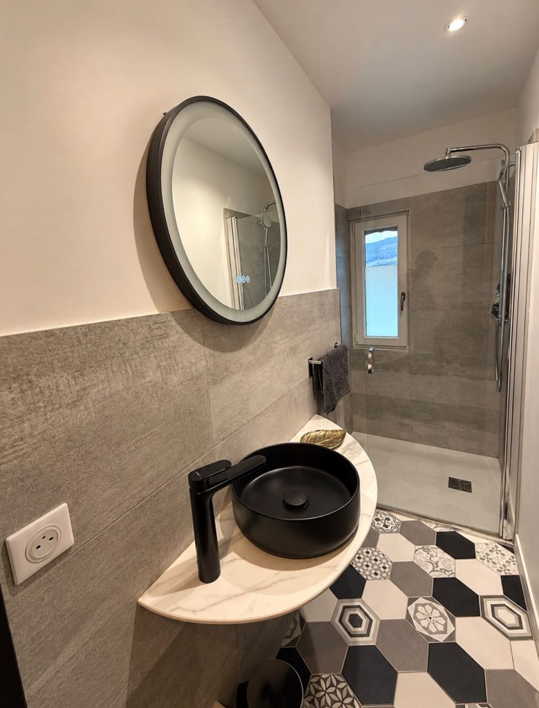 Salle d’eau avec vasque noire et miroir rond, chambre Rosa