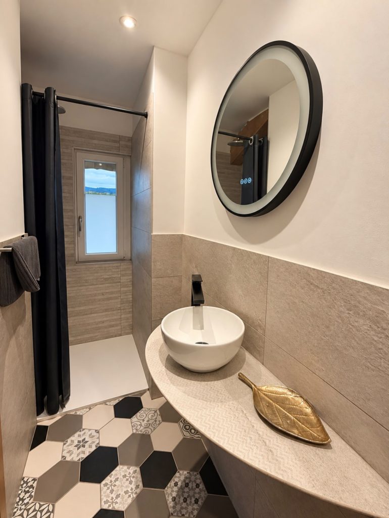 Salle d’eau avec vasque blanche et miroir rond, chambre Verveine